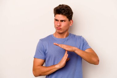 Beyaz arka planda izole edilmiş genç beyaz bir adam bir mola hareketi gösteriyor..