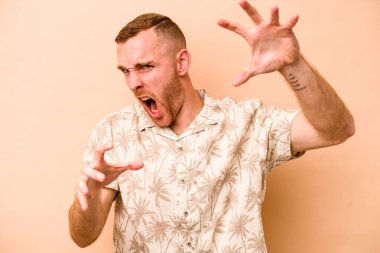 Beyazlı genç adam bej arka planda izole edilmiş gergin elleriyle çığlık atıyor..