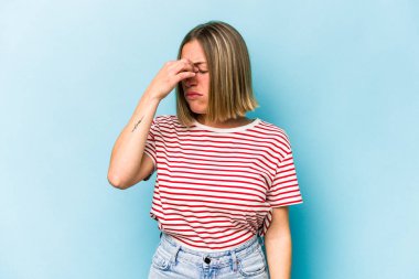 Kafkasyalı genç bir kadın mavi arka planda izole edilmiş, başı ağrıyor, yüzüne dokunuyor..