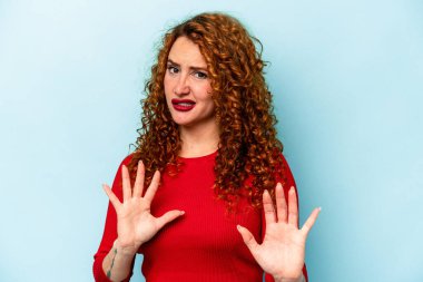 Genç, beyaz, mavi arka planda izole edilmiş bir kadın. İğrenme hareketi gösteren birini reddediyor..