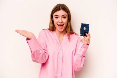 Beyaz arka planda izole edilmiş genç, gayri resmi beyaz kadın hoş bir sürpriz alıyor, heyecanlı ve el kaldırıyor..