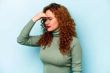 Genç beyaz kadın mavi arka planda izole edilmiş, başı ağrıyor, yüzüne dokunuyor..