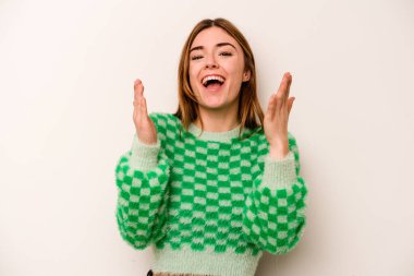 Beyaz arka planda izole genç beyaz kadın yüksek sesle gülüyor elini göğsüne koyuyor..