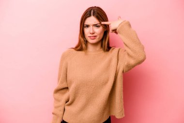 Pembe arka planda izole edilmiş beyaz bir kadın işaret parmağıyla hayal kırıklığı jesti gösteriyor..