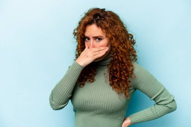 Genç, beyaz, mavi arka planda izole edilmiş, ağzı kapalı, elleri endişeli bir kadın..