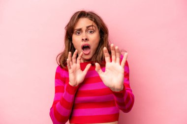 Pembe arka planda izole edilmiş genç beyaz kadın yakın bir tehlike nedeniyle şoka uğruyor.