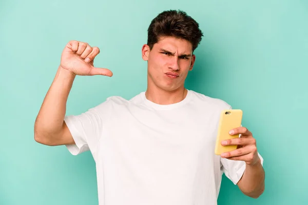 Joven Hombre Caucásico Sosteniendo Teléfono Móvil Aislado Sobre Fondo Azul — Foto de Stock