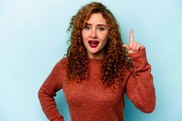 Genç, beyaz, mavi arka planda izole edilmiş bir kadın. Bir fikri, ilham verici bir fikri var..