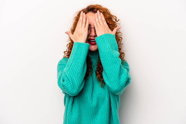 Young ginger caucasian woman isolated on white background having fun covering half of face with palm.