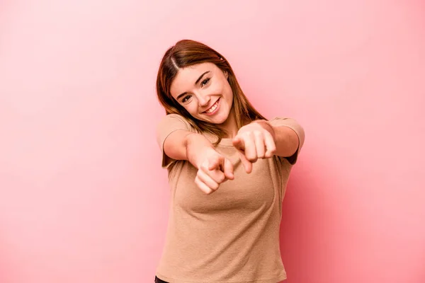 ピンクを背景に指で前を指差す若い白人女性 — ストック写真
