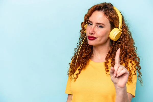 Young Ginger Woman Listening Music Isolated Blue Background Showing Number — Stock Photo, Image