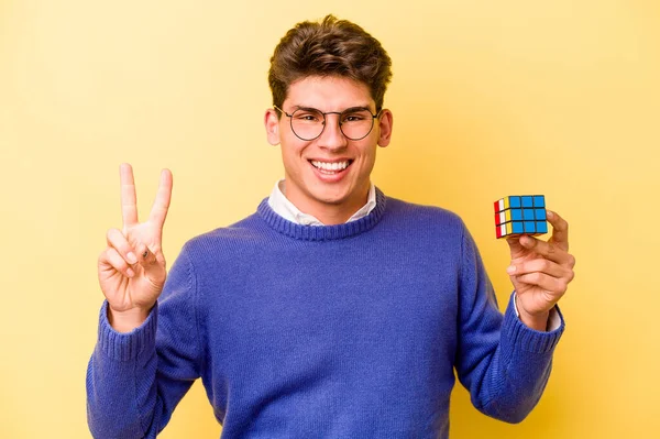 Mladý Běloch Drží Rubiks Kostku Izolované Žlutém Pozadí Ukazující Číslo — Stock fotografie