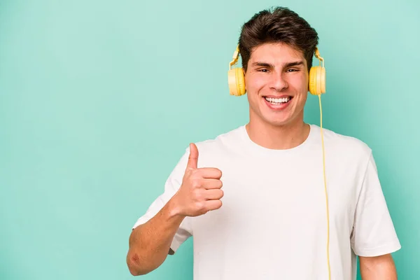 Giovane Uomo Caucasico Ascoltare Musica Isolata Sfondo Blu Sorridente Alzando — Foto Stock