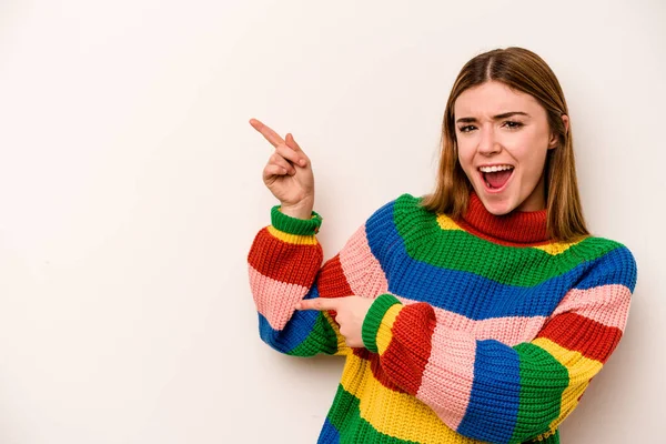 Beyaz arka planda izole edilmiş beyaz tenli genç bir kadın işaret parmağıyla işaret ederek heyecanlanıyor..