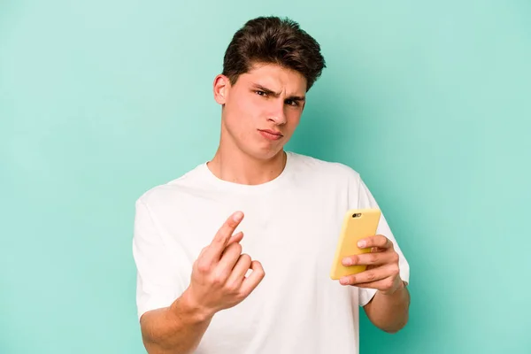 Młody Biały Mężczyzna Trzyma Telefon Komórkowy Odizolowany Niebieskim Tle Wskazując — Zdjęcie stockowe