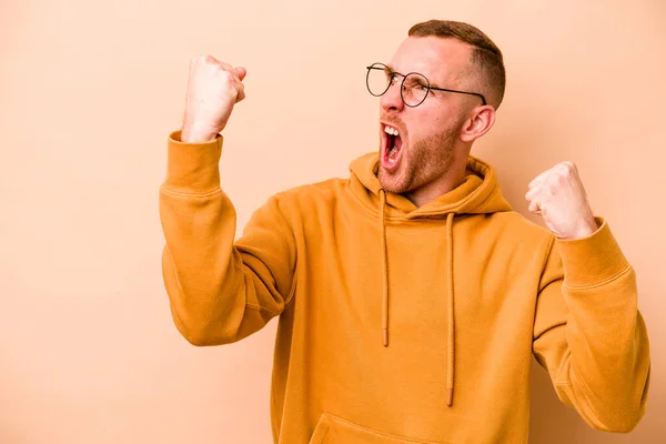 Young Caucasian Man Isolated Beige Background Raising Fist Victory Winner — Stock Photo, Image