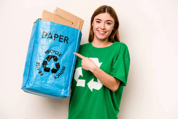 白地に隔離された紙をリサイクルする袋を持っている若い女性は笑顔と脇を指して 空白のスペースで何かを示しています — ストック写真