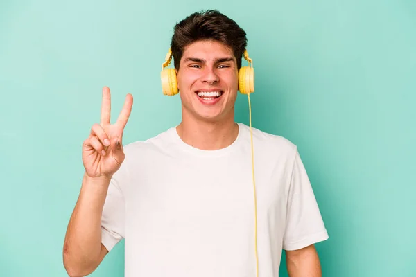 Jovem Caucasiano Ouvindo Música Isolada Fundo Azul Mostrando Número Dois — Fotografia de Stock