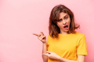 Pembe arka planda izole edilmiş genç beyaz kadın işaret parmaklarıyla fotokopi alanını işaret ederek heyecan ve arzusunu ifade ediyor..