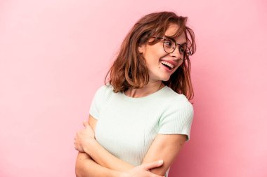 Genç beyaz kadın pembe arka planda izole edilmiş gülüyor ve eğleniyor..