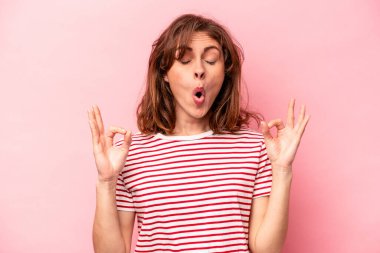 Pembe arka planda izole edilmiş genç beyaz kadın sıkı çalışma gününden sonra dinleniyor, yoga yapıyor..