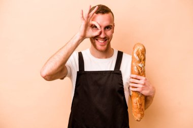 Genç fırıncı beyaz adam bej arka planda izole edilmiş. Heyecanlı. Göze göz hareketi yapıyor..