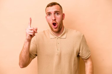 Beyazlı genç bir adam bej arka planda izole edilmiş. Bir fikri, ilham verici bir fikri var..