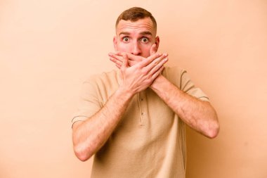 Beyazlı genç bir adam bej arka planda izole edilmiş ağzı kapalı ve elleri endişeli görünüyor..