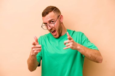 Beyazların arka planında izole edilmiş genç beyaz adam parmaklarıyla ön tarafı işaret ediyor..