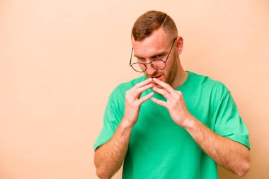 Kafkasyalı genç bir adam, bej arka planda izole edilmiş bir plan kuruyor, bir fikir kuruyor..