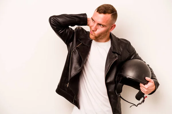 Young caucasian man with a motorcycle helmet isolated on white background touching back of head, thinking and making a choice.