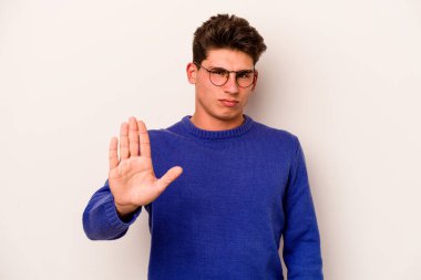 Beyaz arka planda izole edilmiş genç beyaz bir adam gülümseyerek beş numarayı parmaklarıyla gösteriyor..