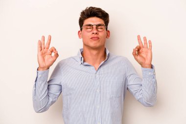 Beyaz arka planda izole edilmiş genç beyaz adam yoğun bir günün ardından rahatlıyor. Yoga yapıyor..