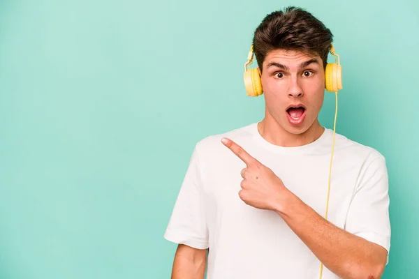 Jonge Kaukasische Man Luisteren Naar Muziek Geïsoleerd Blauwe Achtergrond Wijzen — Stockfoto