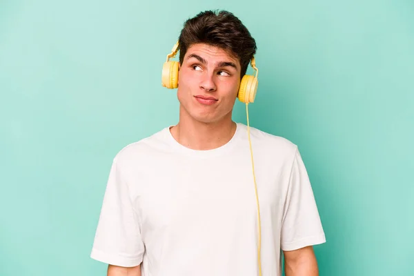 Joven Hombre Caucásico Escuchando Música Aislada Sobre Fondo Azul Soñando — Foto de Stock
