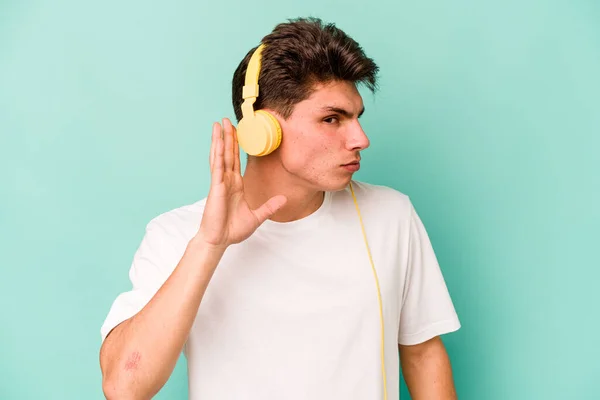 Jonge Kaukasische Man Luisteren Naar Muziek Geïsoleerd Blauwe Achtergrond Proberen — Stockfoto