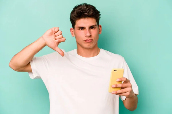 Młody Biały Mężczyzna Trzymający Telefon Komórkowy Niebieskim Tle Wykazujący Niechęć — Zdjęcie stockowe