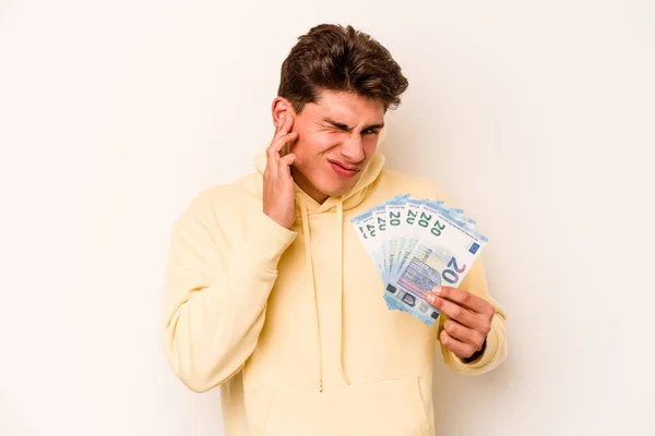 Молодой Кавказский Мужчина Держит Банкноты Белом Фоне Закрывая Уши Руками — стоковое фото