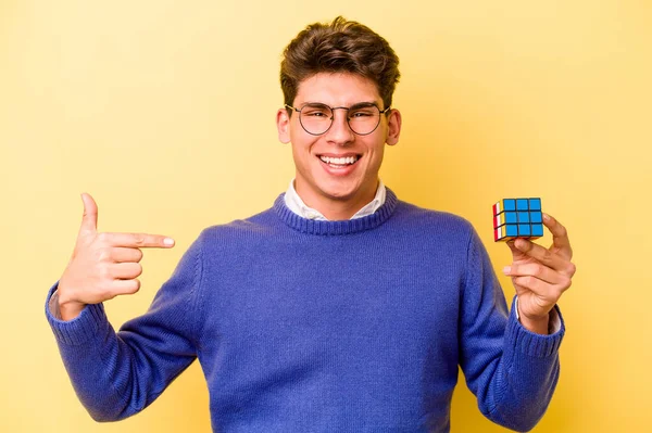 Mladý Běloch Drží Kostku Rubiks Izolované Žlutém Pozadí Osoba Ukazuje — Stock fotografie