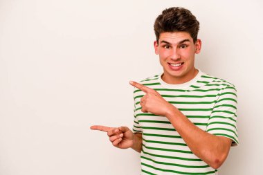 Beyaz arka planda izole edilmiş genç beyaz bir adam işaret parmağıyla fotokopi alanını işaret ederek şok oldu..