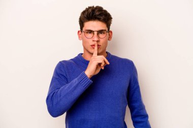 Beyaz arka planda izole edilmiş genç beyaz bir adam ya sır saklıyor ya da sessizlik istiyor..