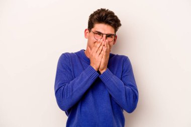 Beyaz arka planda izole olmuş genç beyaz bir adam bir şeye gülüyor, ağızlarını ellerle kapatıyor..