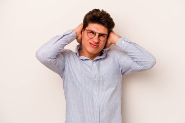 Beyaz arka planda izole edilmiş genç beyaz bir adam kulaklarını elleriyle kapatıyor..