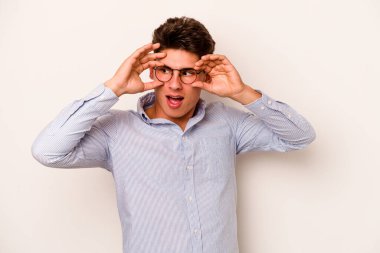 Beyaz arka planda izole edilmiş genç beyaz bir adam bir başarı fırsatı bulmak için gözlerini açık tutuyor..