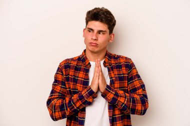 Beyaz arka planda izole edilmiş genç beyaz adam dua ediyor, bağlılık gösteriyor, dindar biri ilahi ilham arıyor..