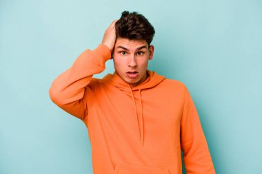 Mavi arka planda izole genç beyaz adam şok oldu, o önemli bir toplantı hatırladı.