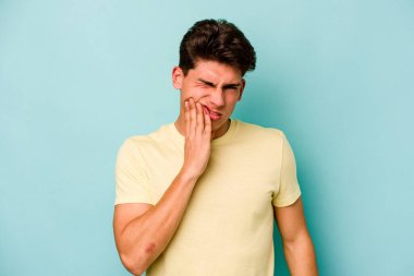 Mavi arka planda izole genç beyaz adam güçlü bir diş ağrısı, azıdişi ağrısı var..