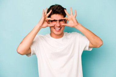 Kafkasyalı genç adam mavi arka planda izole edildi. Heyecanlı görünüyor..