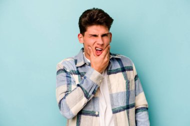 Mavi arka planda izole genç beyaz adam güçlü bir diş ağrısı, azıdişi ağrısı var..