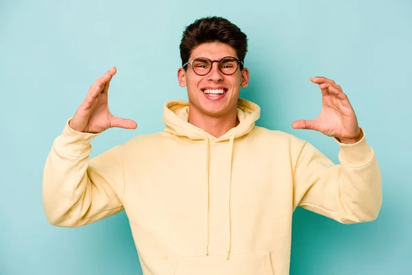 Young Caucasian Man Isolated Blue Background Holding Something Palms Offering — Stock Photo, Image